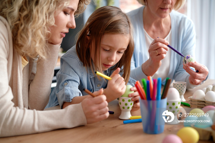 Three generations of women during painting Easter eggs at home