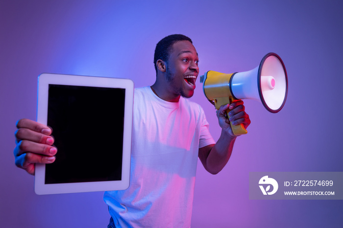 African Guy Making Announcement With Loudspeaker And Holding Digital Tablet, Neon Lighting