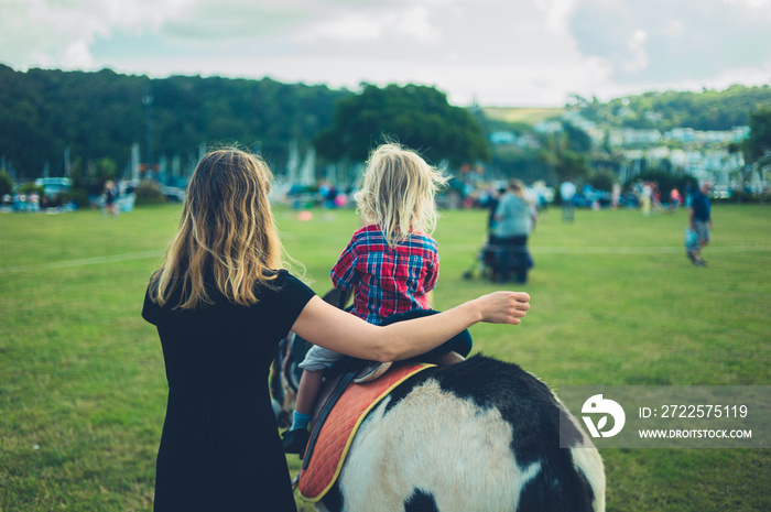 Little toddler riding a donkey at the fair