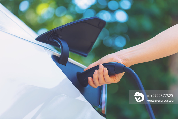 Person charging an electric vehicle with green background