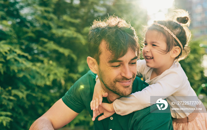 Outdoor image of happy cute little girl smiling and playing with her father. Handsome dad and pretty