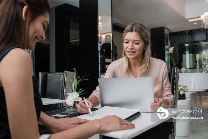 Two businesswomen having meeting at hotel lobby.