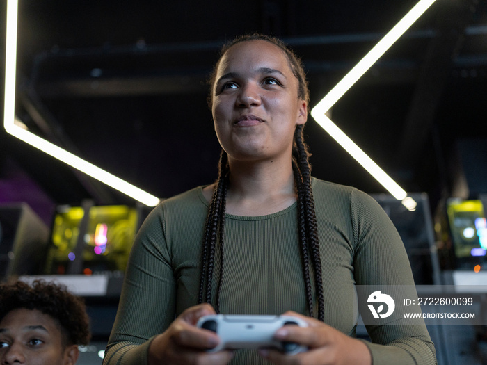 Portrait of young woman playing video games in gaming club