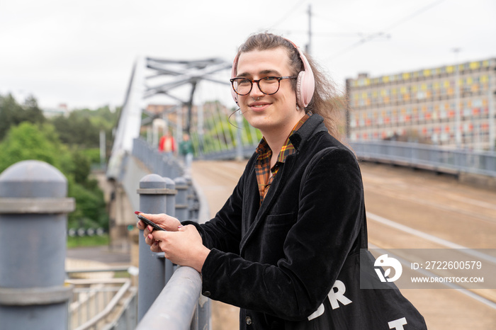 Portrait of smiling man listening music on city street