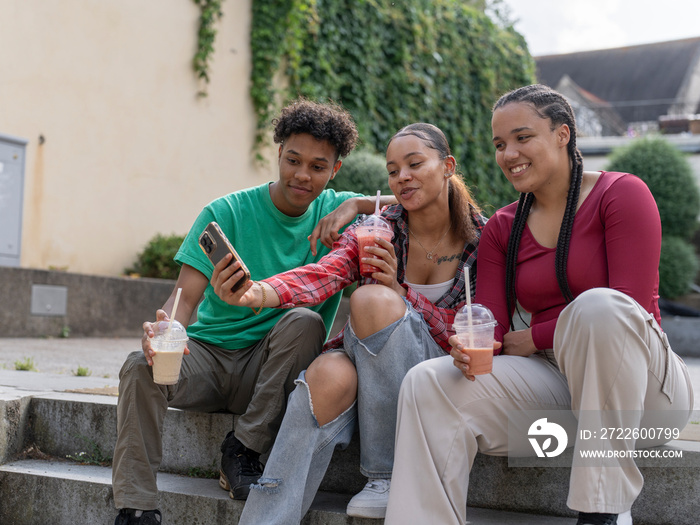 Friends taking selfie while drinking smoothie on steps