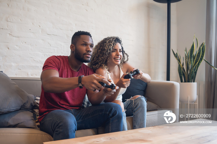 Young couple palying video games together at home.