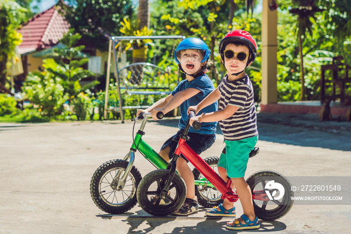 Two little boys children having fun on Balance Bike on a country tropical road