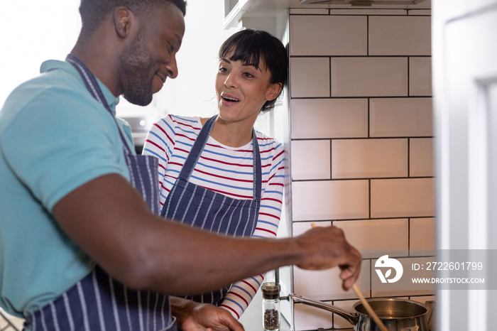 Happy multiracial young couple cooking food together at home