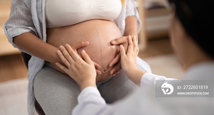 Happy Asian pregnant woman with her doctor in the examination room