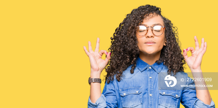 Young beautiful woman with curly hair wearing glasses relax and smiling with eyes closed doing meditation gesture with fingers. Yoga concept.