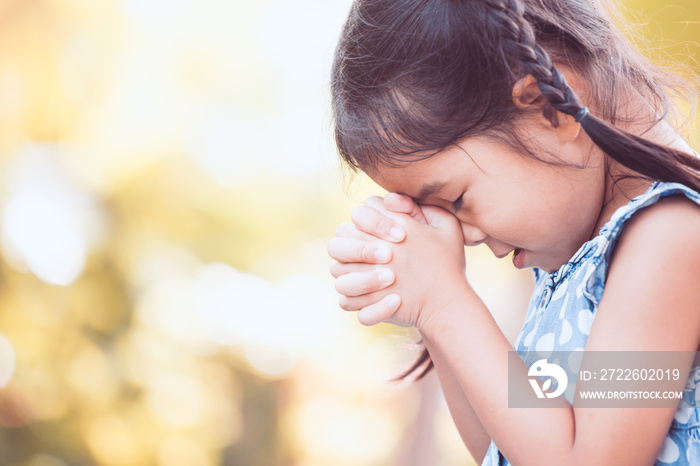 Cute asian little child girl praying with folded her hand for faith,spirituality and religion concept