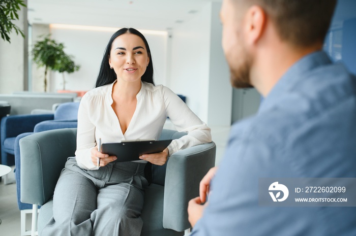 Business concept. Young dark-haired woman sitting in front of mature cheerful office manager on job interview, having relaxing talk about her experience and study degree.