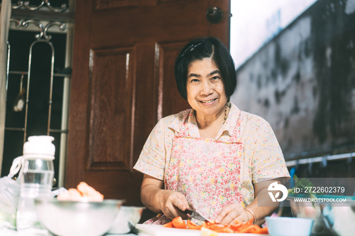 Aunthentic portrait of happy asian elderly woman cooking for family at local traditional kitchen style at home.