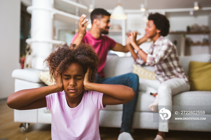 Sad, desperate african american girl during parents quarrel,angry parents fighting.