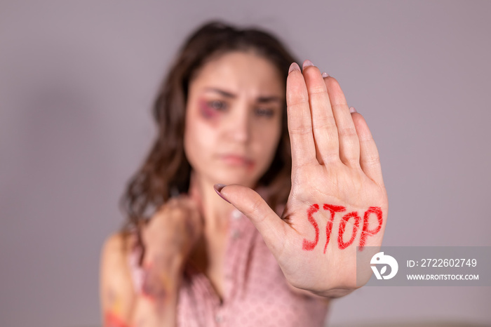 Domestic violence, protesting and people concept - brunette woman expressing denial with STOP on her hand on grey room