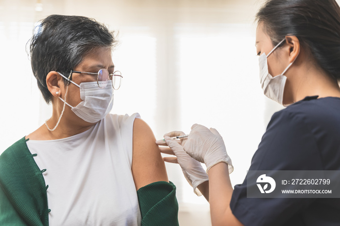 People getting a vaccination to prevent pandemic concept. Mature Woman in medical face mask  receiving a dose of immunization coronavirus vaccine from a nurse at the medical center hospital