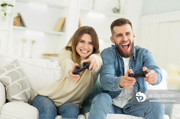 Fans of video games. Overjoyed couple playing on game console