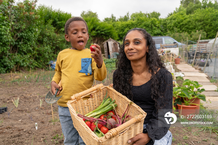 Portrait of mother with son holding basket with fresh vegetables