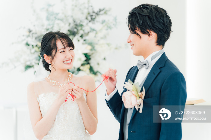 結婚式場で赤い糸で結ばれる新郎新婦（ブライダル・ウェディング）