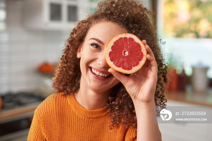 Portrait of woman covering her eye with grapefruit