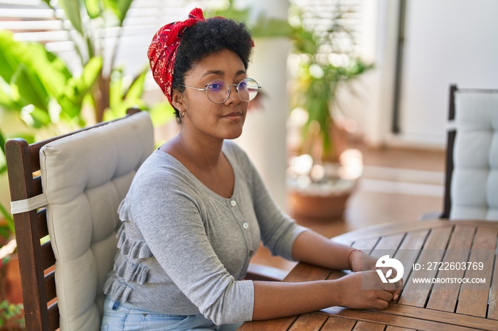 African american woman smiling confident sitting on table at home terrace