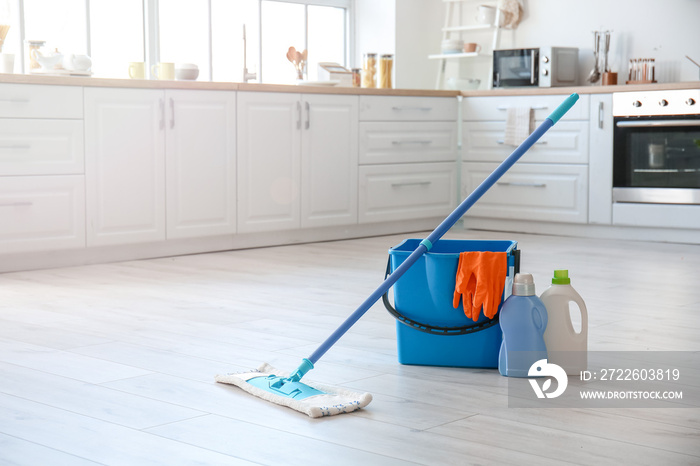 Set of cleaning supplies on floor in kitchen