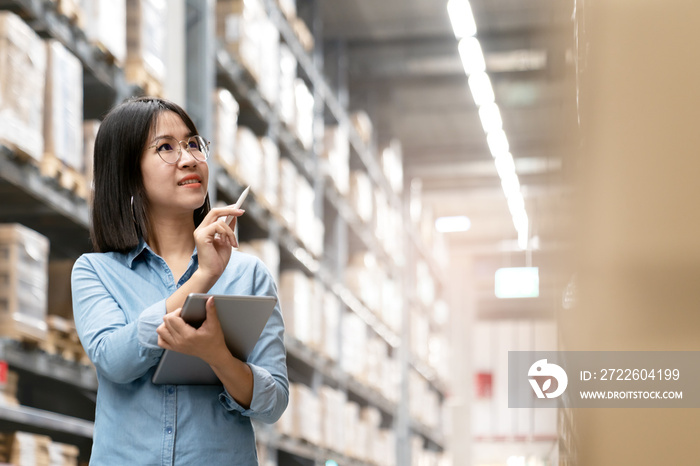 Candid of young attractive asian woman, auditor or trainee staff working in warehouse store counting or stocktaking inventory by smart tablet. Asian entrepreneur, small business or SME concept.