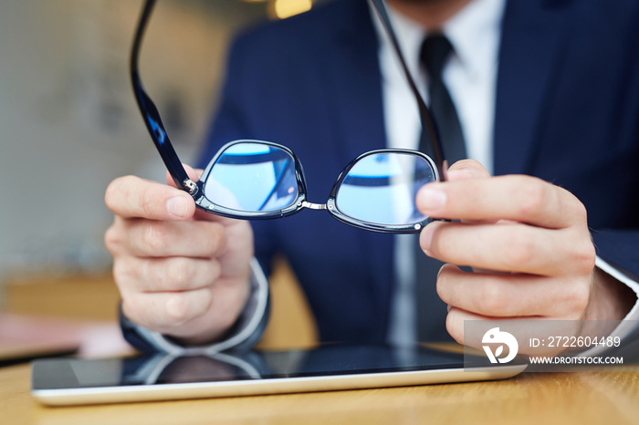 Human hands holding eyeglasses over touchpad