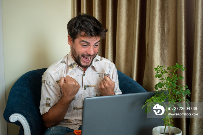 Hombre contento festejando después de realizar una compra on-line con su laptop