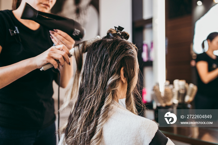 Beautiful brunette woman with long hair at the beauty salon getting a hair blowing. Hair salon styling concept.