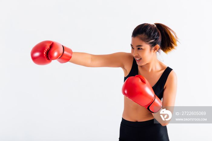 Portrait of a young smiling female boxer punching on white isolated background with copy space. Asian woman doing boxing exercise with happy look.