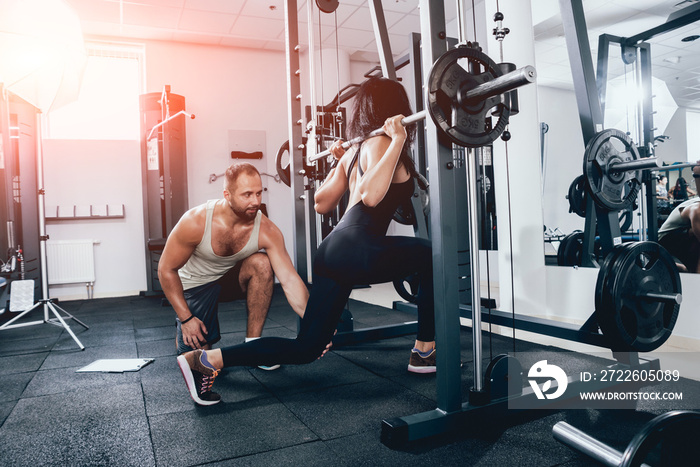 Fitness woman exercising with fitness trainer in gym. Personal fitness instructor.