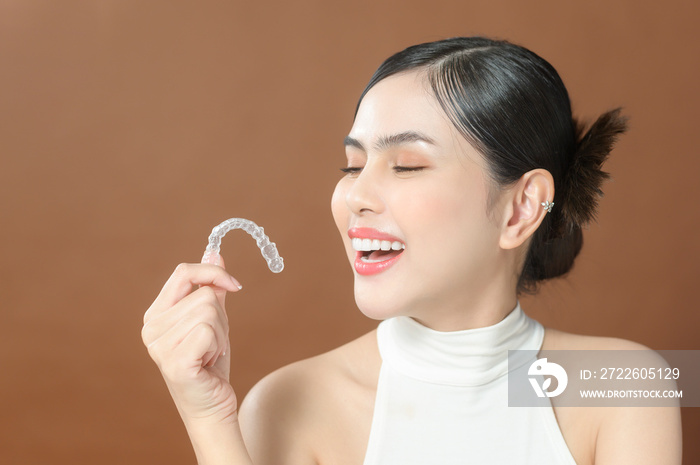 A young woman with beautiful teeth is holding Invisalign, healthy dental concept