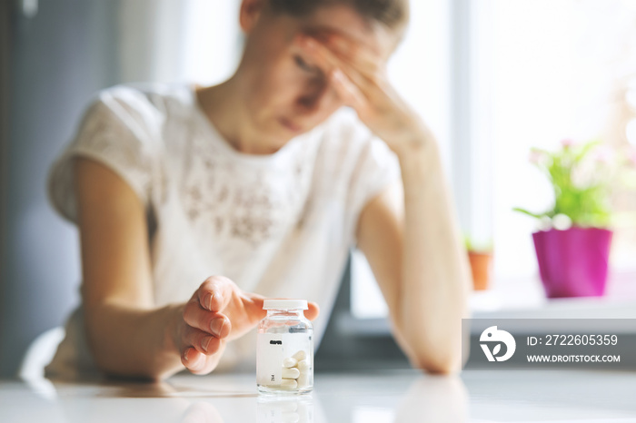 woman with headache reaching for painkiller pills. migraine, cephalalgia and stress concept