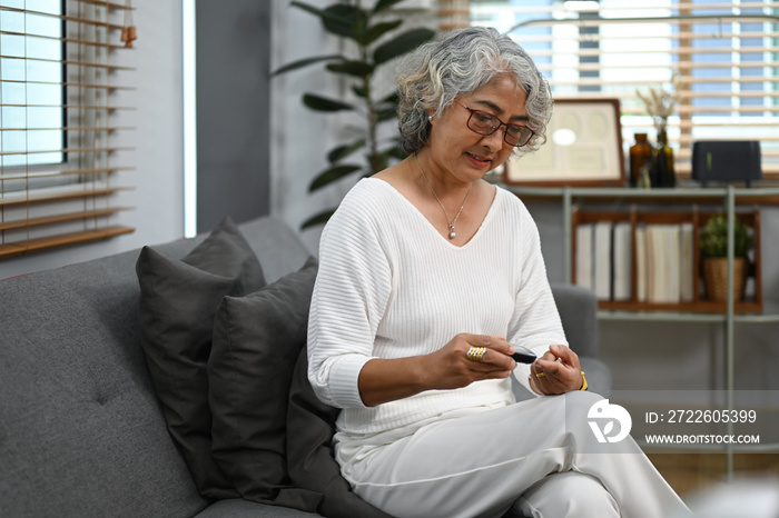 Image of diabetic middle age woman checking blood glucose levels with a glucose meter. Diabetes and health care concept