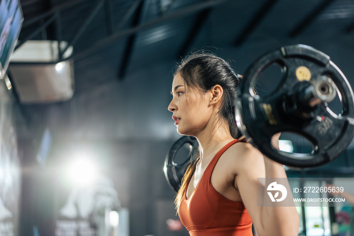 Asian sportswoman slowly lift up weight machine or barbell in stadium.