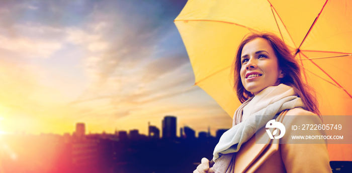 season, weather and people concept - beautiful happy young woman with yellow umbrella over sunset in autumn city of tallinn background