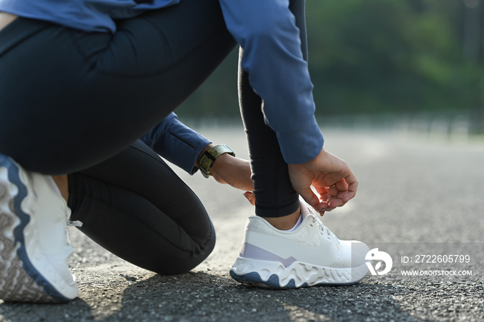 Cropped view of sportswoman tying shoelace before exercises outdoors. Fitness, sport and healthy lifestyle concept