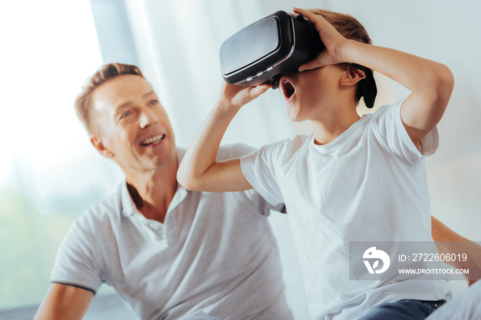 So realistic. Delighted positive surprised boy wearing 3d glasses and looking into them while enjoying his new technology