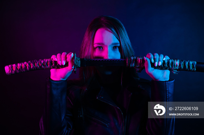 Cyber girl in a black leather jacket at dusk holds a katana. A woman in a club with a colored pink-blue light holds an Asian sword.