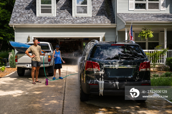 Air Force service member washes his vehicles with his sons in the driveway.