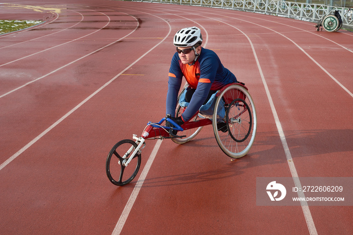 Handicapped sportsman in helmet and sunglasses sitting in racing wheelchair