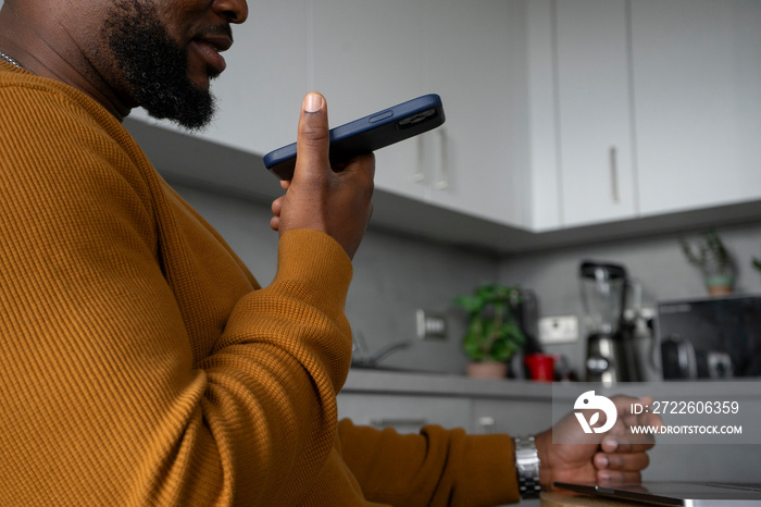 Mid section of man using smart phone in kitchen