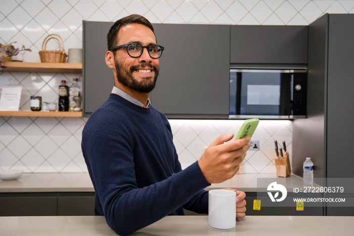 Portrait of man using smart phone in kitchen