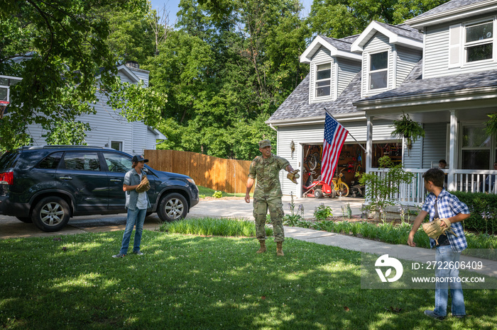 Air Force service member plays catch with sons after coming home from work in uniform.