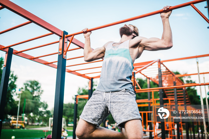 strong athlete doing pull-up on horizontal bar. Muscular man doing pull ups on horizontal bar in park. Gymnastic Bar During Workout. training strongmanoutdoor park gym. Man Doing Exercise gym Outdoor