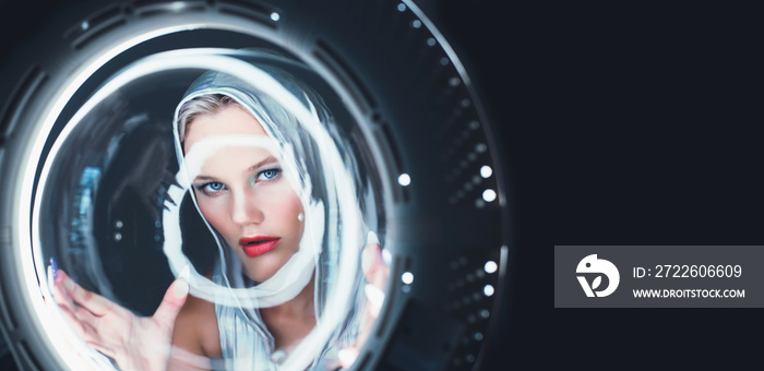 Attractive young blonde looks like in the porthole of a spaceship. Futuristic portrait.