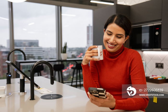 Woman using smart phone in office kitchen