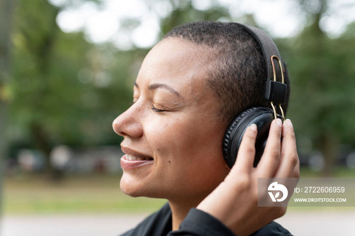 Close-up of smiling woman with headphones in park