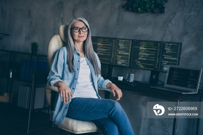 Portrait of attractive cheery experienced grey-haired woman coder at loft style interior work place station indoors